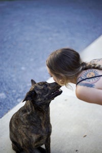 a woman with tattoos kissing a dog