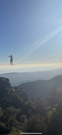 a man is walking on a tightrope over a mountain
