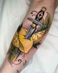 a tattoo with a sword and lemons on the forearm