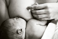 a black and white photo of a woman breastfeeding a baby