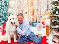 a man and his dog posing in front of a christmas tree