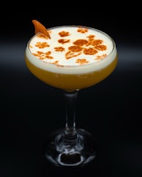 a cocktail with an orange garnish on a black background