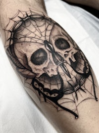 a black and grey tattoo of a skull and spider web