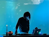 a dj in front of a laptop in a dark room