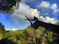 a person holding a pair of scissors in front of a rainbow