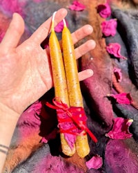 a hand holding two yellow candles on top of a piece of cloth