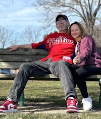 a man and woman sitting on a bench in a park
