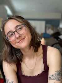 a woman with tattoos and glasses sitting in a living room