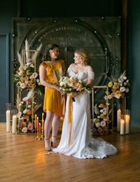 two brides posing for a photo in front of a wedding cake