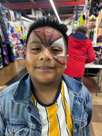 a boy with spider - man face paint in a store