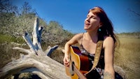 a woman playing an acoustic guitar in a field
