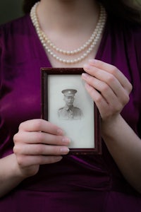 a woman holding a picture of a man in uniform