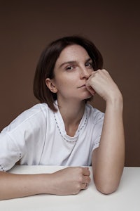 a woman sitting at a table with her hand on her chin
