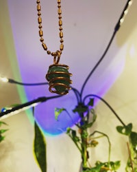 a green stone pendant hanging from a gold chain