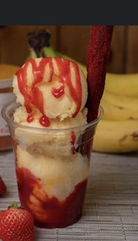 a cup of ice cream with strawberries and bananas