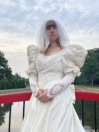 a woman in a wedding dress standing on a bridge
