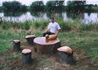 a man sitting next to a tree stump with a dog on it