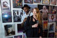a man and woman standing in front of a wall of art