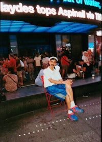 a man sitting in a chair in front of a sign