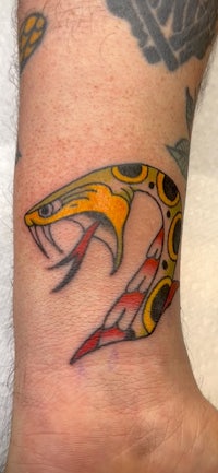 a tattoo of a snake on the wrist