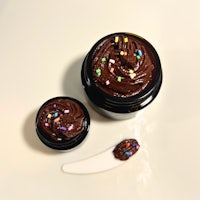 a jar of chocolate icing with sprinkles and a spoon