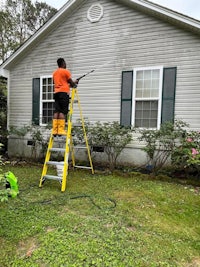 a man spraying a house with a pressure washer