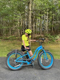 a woman standing next to a blue bike in the woods