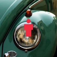 a green vw beetle with a man on the headlight