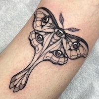 a black and white moth tattoo on the forearm