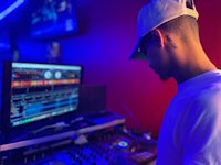 a dj in a hat working at a dj booth