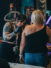 two women getting tattoos at a convention