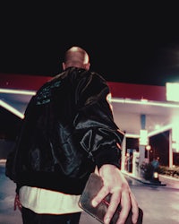 a man in a black jacket standing in a gas station