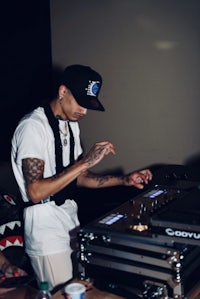 a man with tattoos is playing a dj at a party