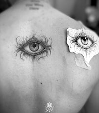 a black and white photo of an eye tattoo on a man's back