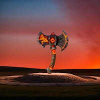 a large axe is sitting on top of a rock in front of a sunset