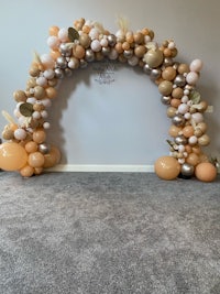 a balloon arch decorated with gold and peach balloons