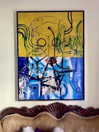 an abstract painting hangs above a couch in a living room