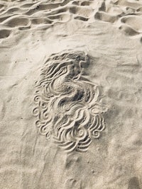 a drawing of a mermaid in the sand