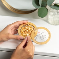 a woman is holding a tin of pearls on a table