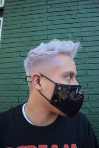 a man with purple hair wearing a face mask