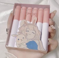 a hand holding a box of pens with a bunny in it