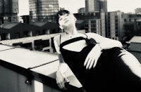 a woman in a black dress posing on a rooftop
