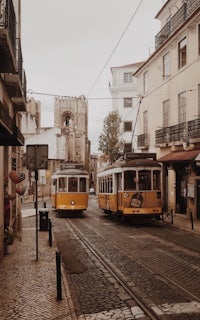 two yellow trams on a cobblestone street in lisbon