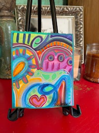 a colorful painting on a easel next to a vase