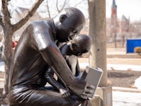 a statue of a man and a child reading a book