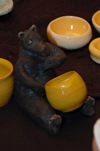 a black bear sitting on a table next to a set of bowls