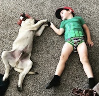 a boy laying on the floor next to a dog