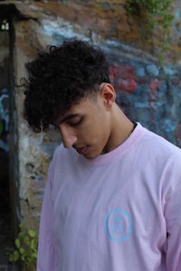 a young man wearing a pink long sleeve t - shirt
