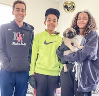 three young people posing for a picture with a pug
