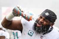 a miami dolphins player drinking from a water bottle
